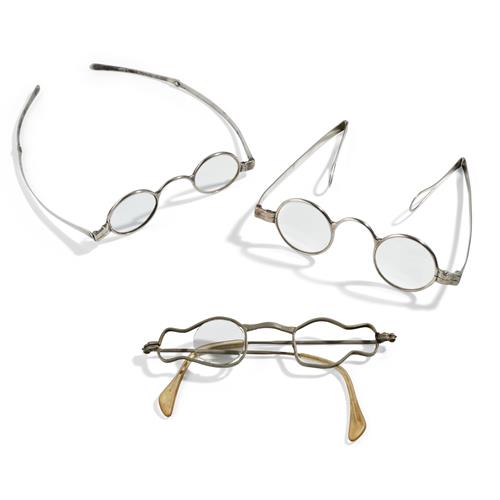 87 · TWO SILVER READING GLASSES AND A BRASS CHINESE EXAMPLE