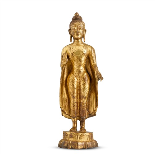56 · A NEPALESE GILT-BRONZE STANDING FIGURE OF BUDDHA SHAKYAMUNI, 17TH/18TH CENTURY